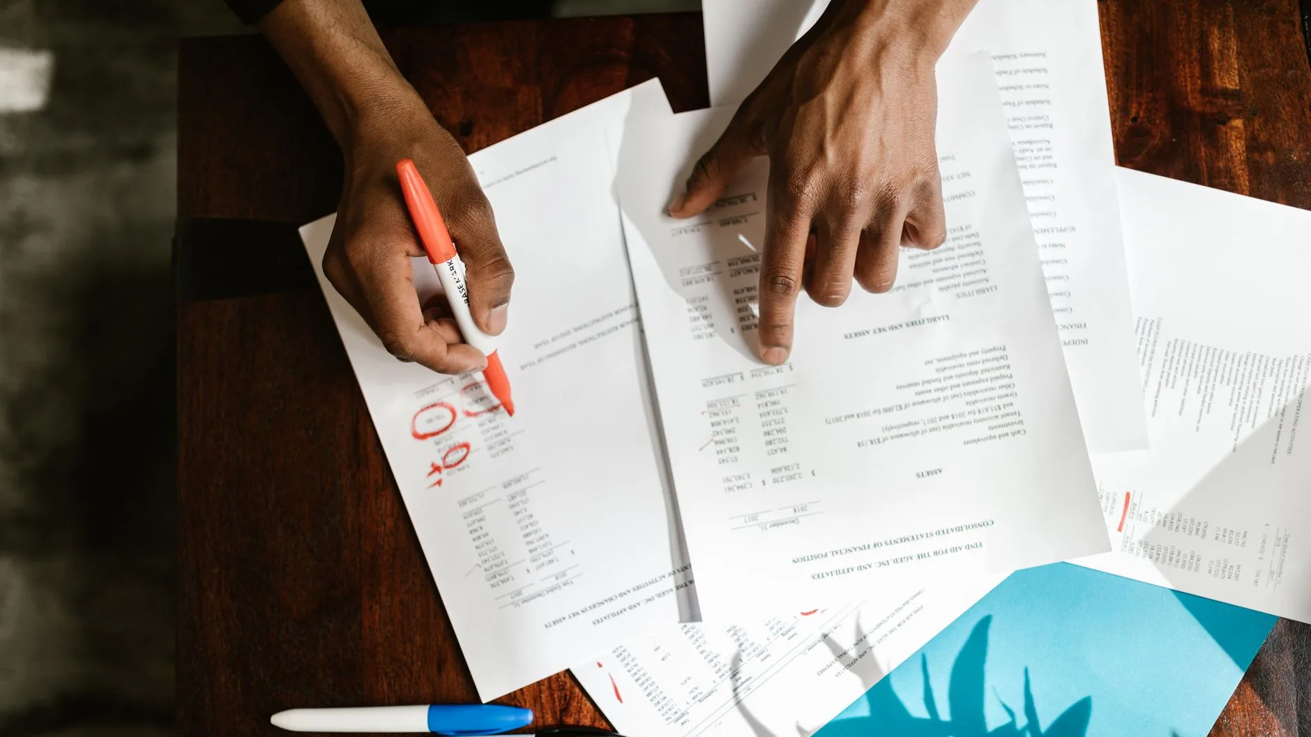 Overhead view of hands highlighting financial documents on a desk.