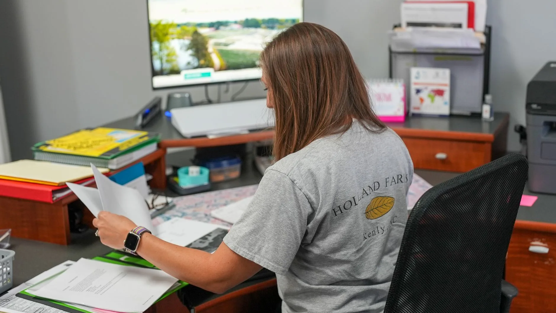 Woman organizing papers in a modern office setting.